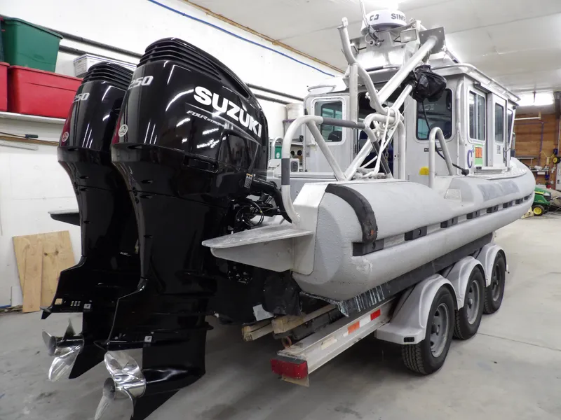Slide: The Image of 2005 SAFE Boats Defender 25 with dual Suzuki engines on a trailer in a garage. - 13
