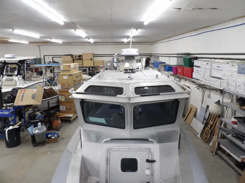 Slide: The Image of 2005 SAFE Boats Defender 25 in a cluttered garage with boxes and equipment. - 23