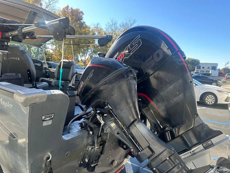 Slide: The Image of 2019 Lund 2000 Sport Angler boat with dual outboard motors in a parking lot. - 16