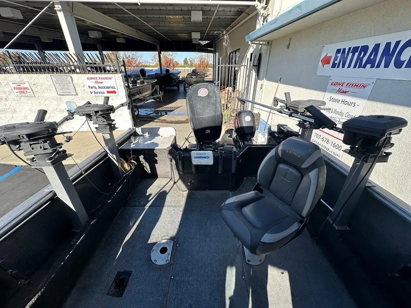 Slide: The Image of 2019 Lund 2000 Sport Angler boat interior with seating and motor, parked under shelter. - 17
