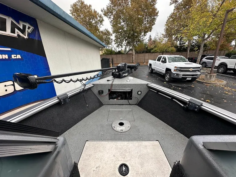 Slide: The Image of 2019 Lund 2000 Sport Angler boat interior with fishing equipment, parked near trucks. - 29
