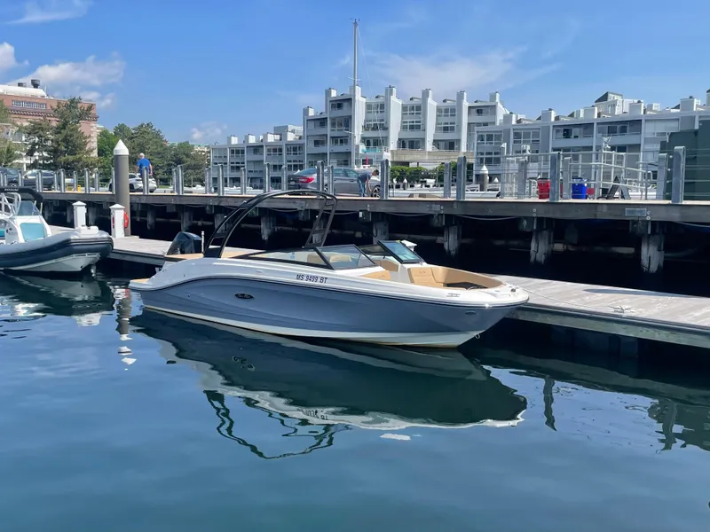 Slide: The Image of 2023 Sea Ray SPX 230 OB boat docked at marina with modern buildings in background. - 0