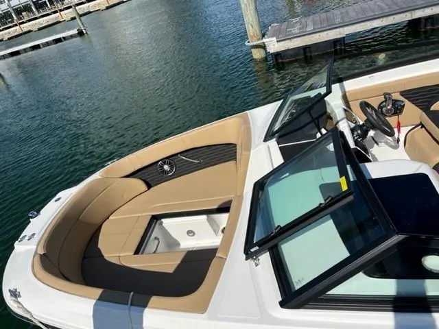 Slide: The Image of 2023 Sea Ray SPX 230 OB boat with tan seating, docked by the water. - 2