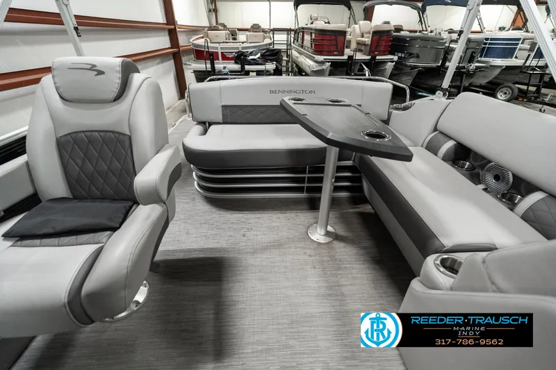 Slide: The Image of 2022 Bennington 22 LSB boat interior with gray seating and table in showroom. - 13