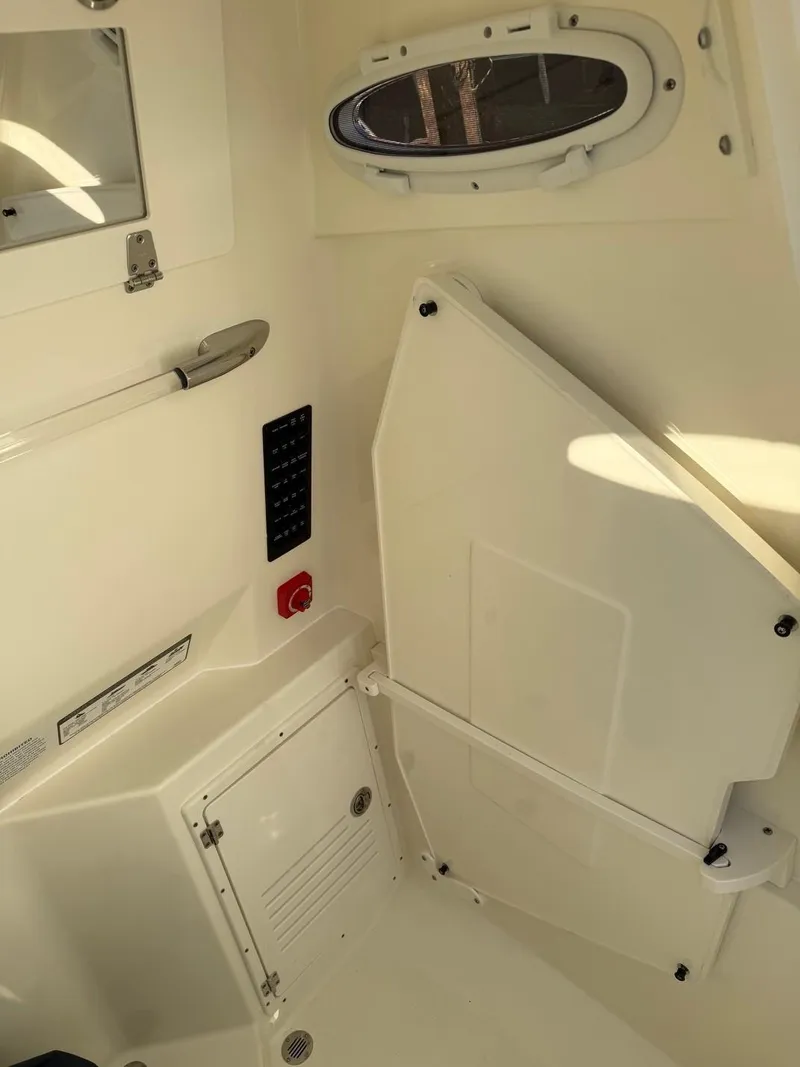 Slide: The Image of 2025 Cobia 265 Open Center Console interior with storage compartment and porthole. - 16