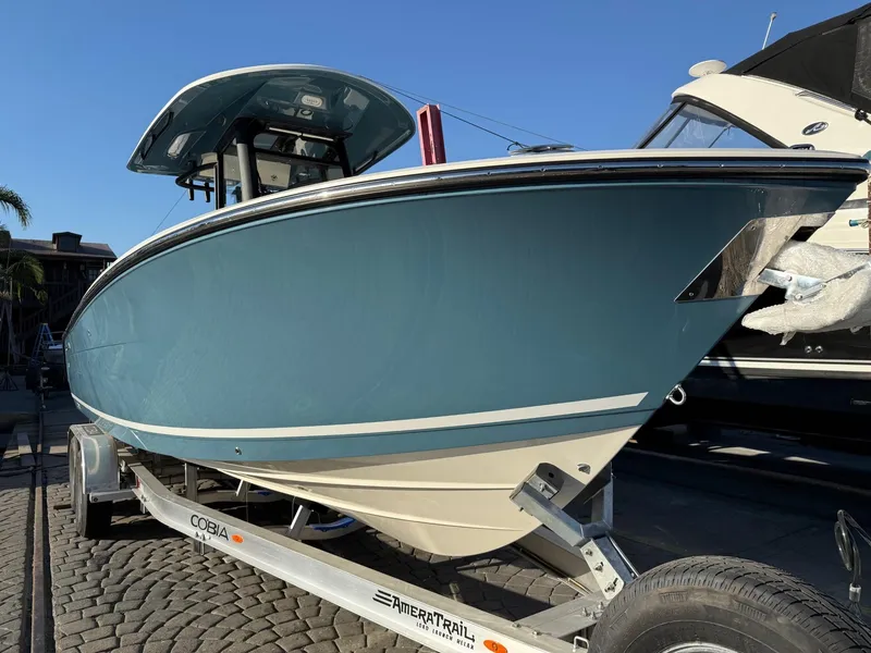 Slide: The Image of 2025 Cobia 265 Open Center Console boat on trailer, blue hull, sunny day. - 2