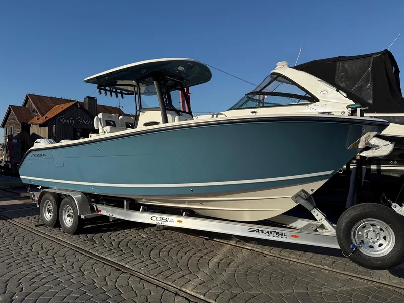 Slide: The Image of 2025 Cobia 265 Open Center Console boat on trailer, blue hull, sunny day. - 3