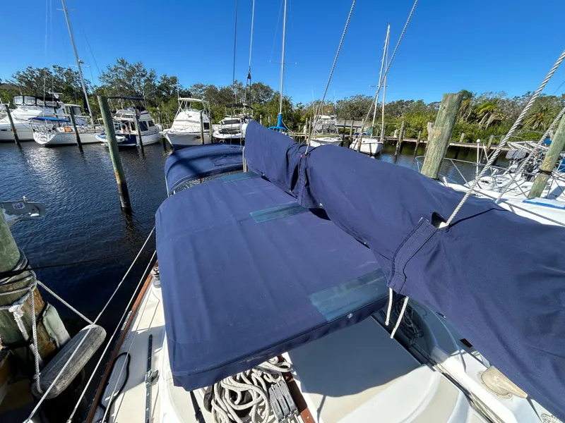 Slide: The Image of 1985 Tartan sailboat docked at marina with blue covers and clear sky. - 23