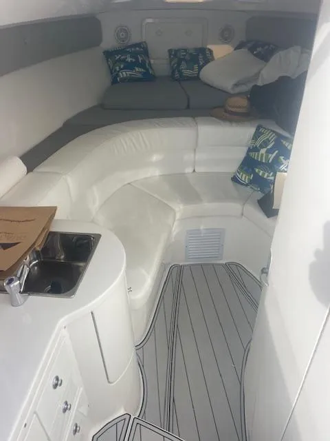 Slide: The Image of 2008 Intrepid Cuddy interior with white seating, compact kitchen, and decorative pillows. - 10