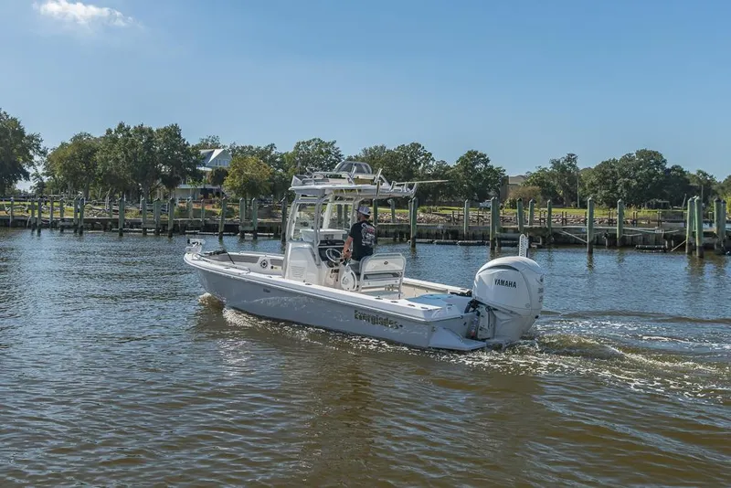 Slide: The Image of 2023 Everglades 243cc Sport Station boat cruising on a sunny day near a dock. - 14