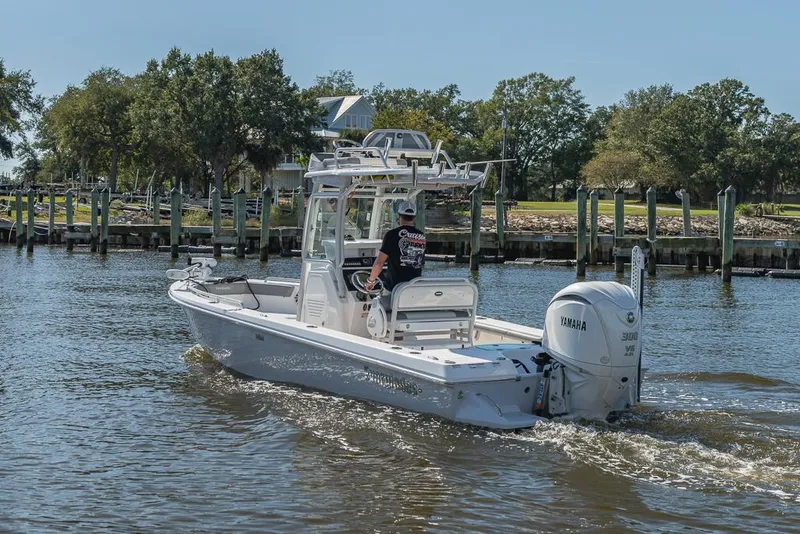Slide: The Image of 2023 Everglades 243cc Sport Station boat cruising on a sunny day near a dock. - 15