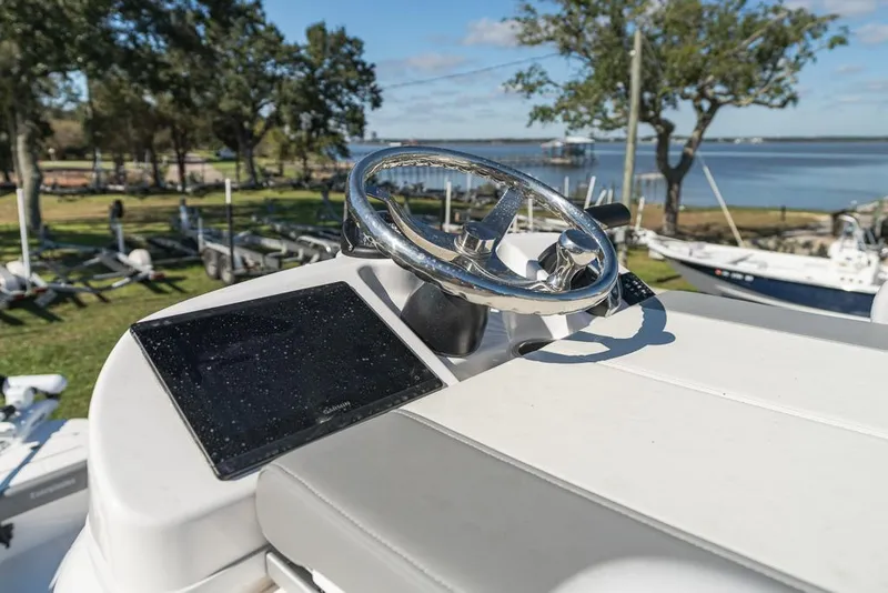 Slide: The Image of 2023 Everglades 243cc Sport Station helm with steering wheel and display, near waterfront. - 19