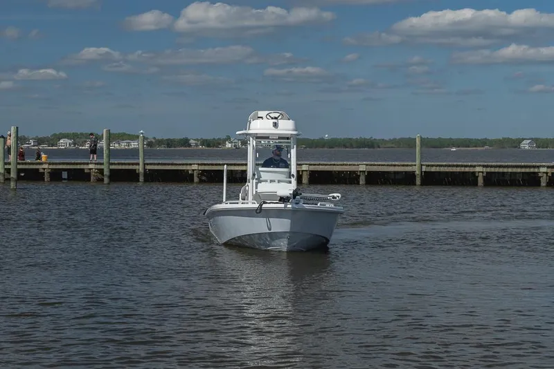 Slide: The Image of 2023 Everglades 243cc Sport Station boat on calm water near a dock. - 2