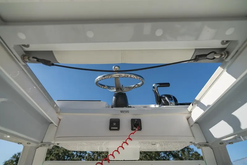Slide: The Image of 2023 Everglades 243cc Sport Station helm with steering wheel and controls, under clear blue sky. - 20