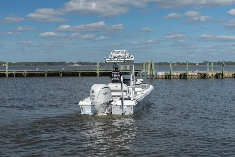 Slide: The Image of 2023 Everglades 243cc Sport Station boat on calm water near a dock. - 26
