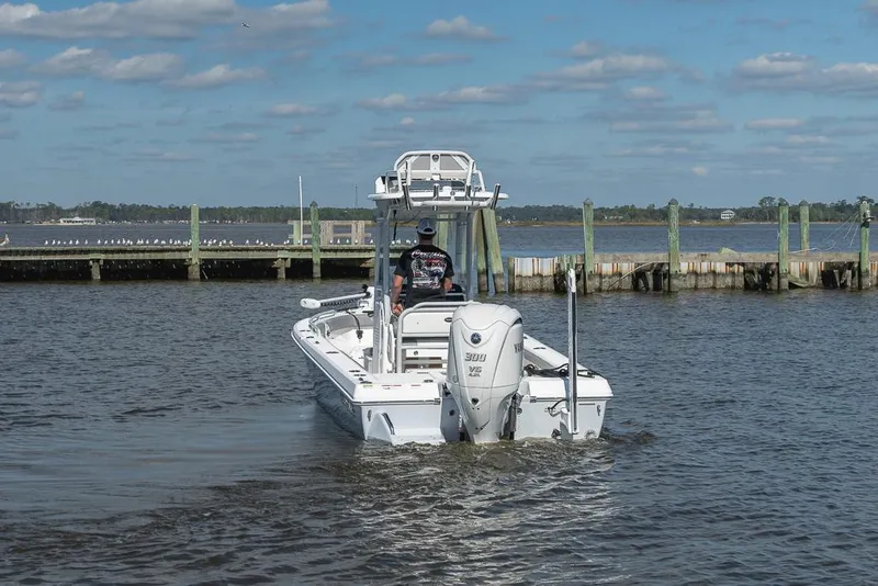 Slide: The Image of 2023 Everglades 243cc Sport Station boat on calm water near a wooden dock. - 27