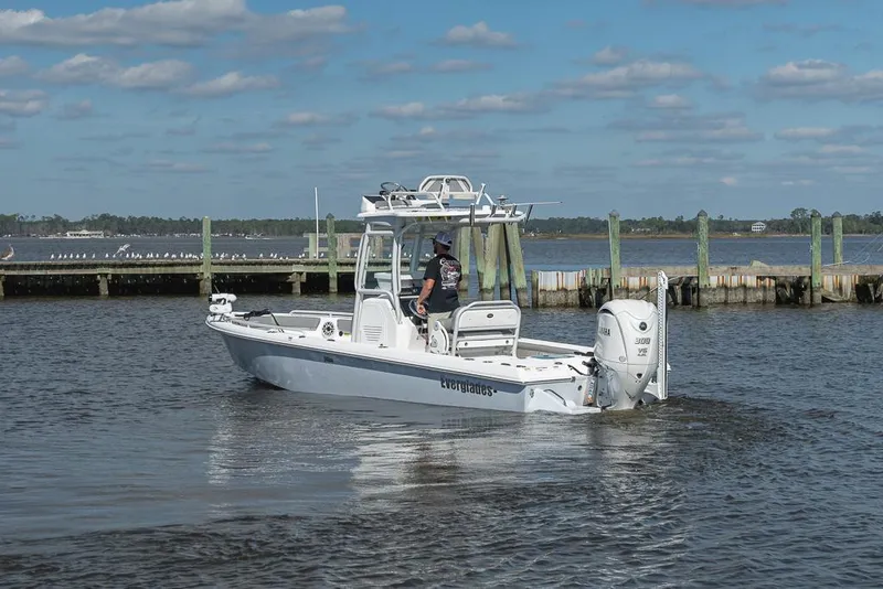 Slide: The Image of 2023 Everglades 243cc Sport Station boat on calm water near a dock. - 28