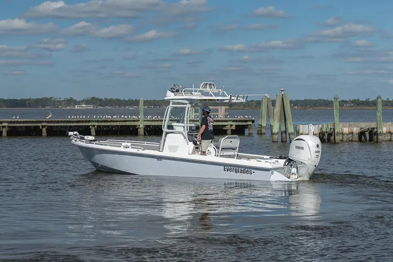 Slide: The Image of 2023 Everglades 243cc Sport Station boat on calm water near a dock. - 29