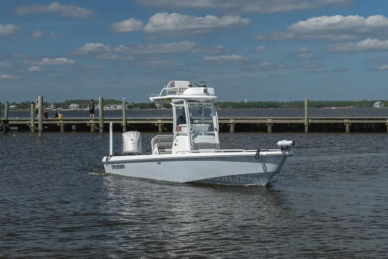 Slide: The Image of 2023 Everglades 243cc Sport Station boat on calm water near a dock under a blue sky. - 3