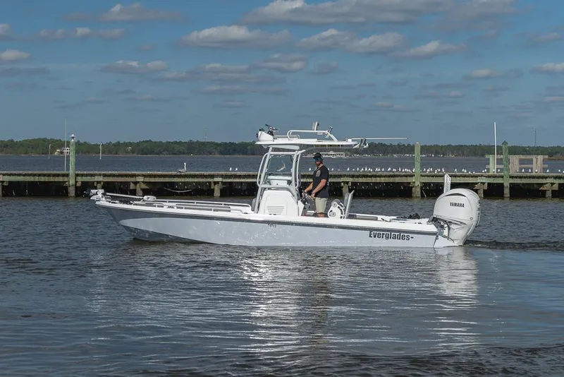 Slide: The Image of 2023 Everglades 243cc Sport Station boat on calm water near a dock. - 30
