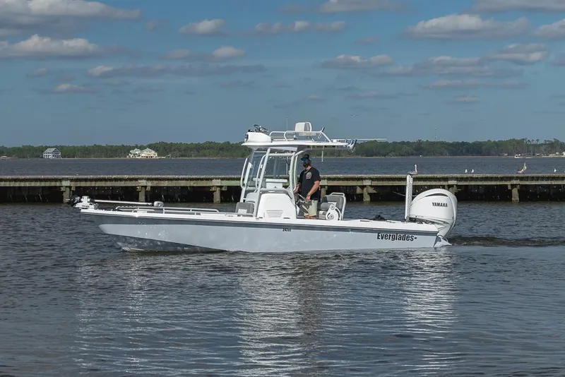 Slide: The Image of 2023 Everglades 243cc Sport Station boat cruising on a calm lake under a blue sky. - 31