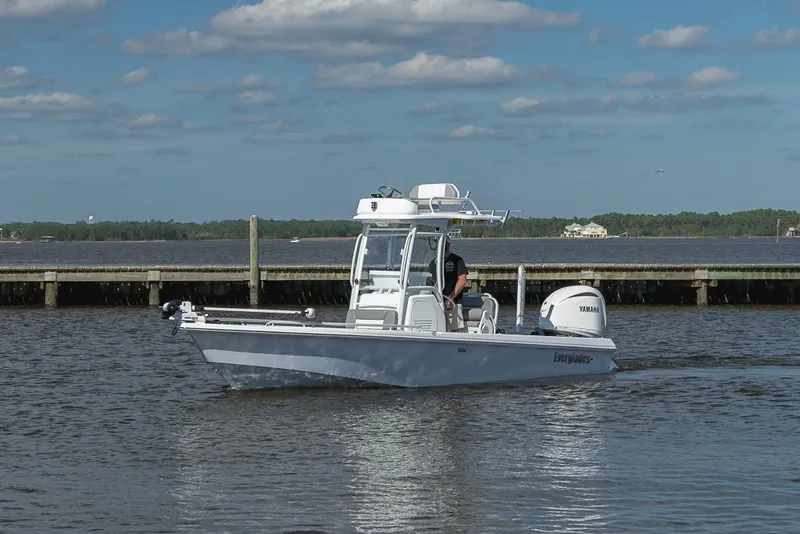 Slide: The Image of 2023 Everglades 243cc Sport Station boat cruising on a calm lake under a blue sky. - 32
