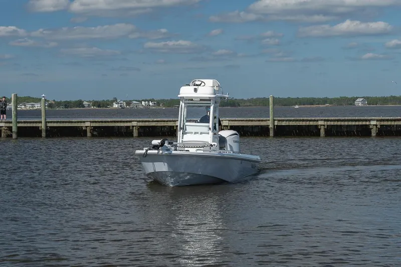 Slide: The Image of 2023 Everglades 243cc Sport Station boat on calm water near a dock. - 33