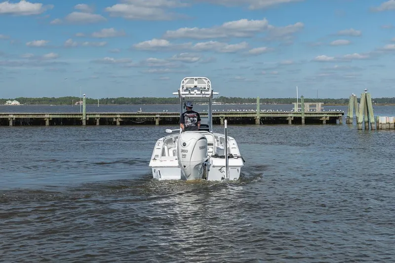 Slide: The Image of 2023 Everglades 243cc Sport Station boat on water near a dock under a blue sky. - 7