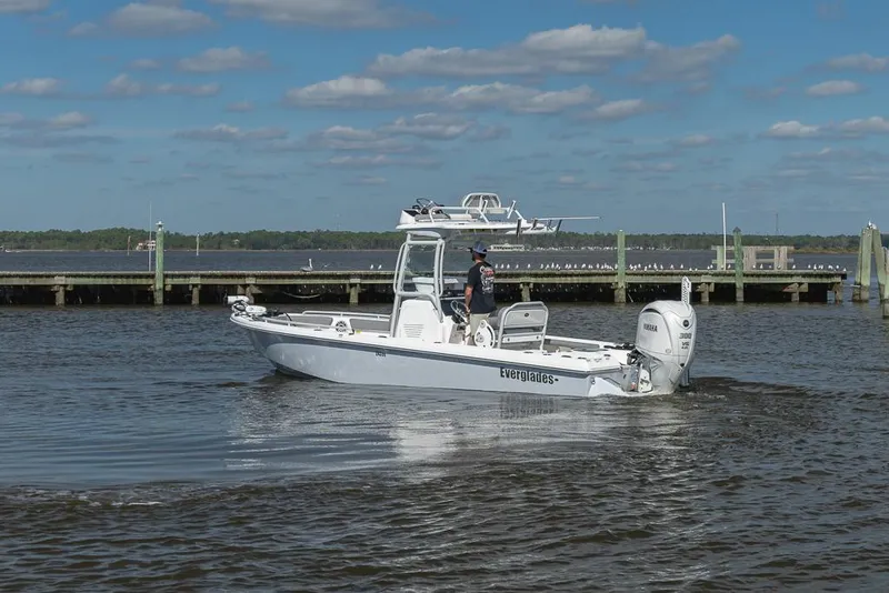 Slide: The Image of 2023 Everglades 243cc Sport Station boat cruising on a sunny day near a dock. - 8