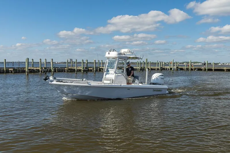Slide: The Image of 2023 Everglades 243cc Sport Station boat cruising on a sunny day near a dock. - 9