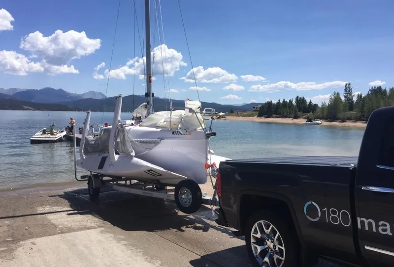 Slide: The Image of Truck towing Corsair 760 sailboat at lakeside ramp, clear sky, mountains in background. - 9