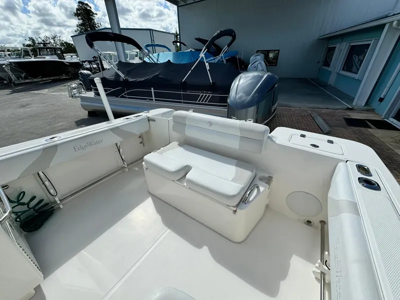 Slide: The Image of 2013 Edgewater 245 CX boat interior with seating, docked near other boats. - 10