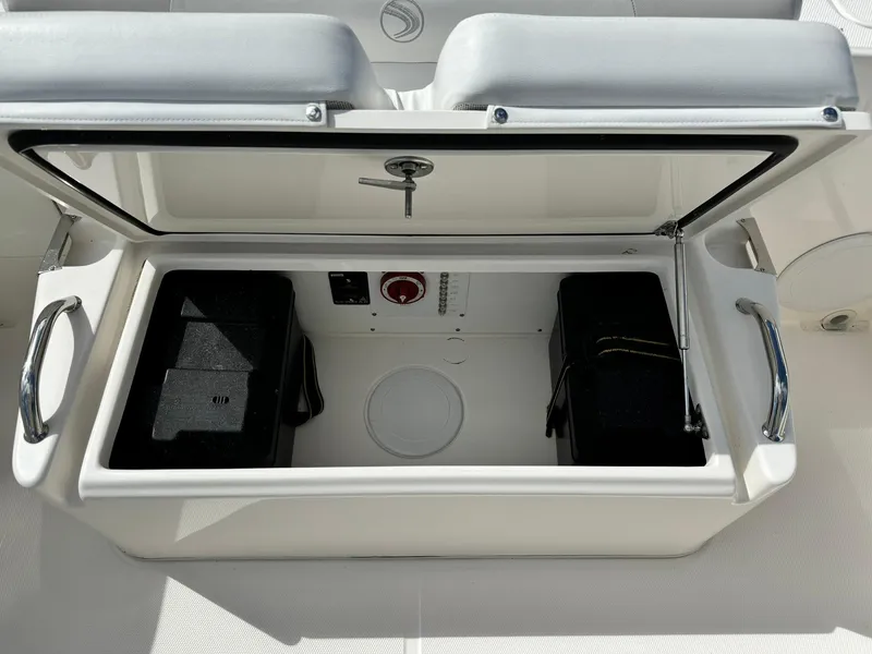 Slide: The Image of Open storage compartment on 2013 Edgewater 245 CX boat, featuring dual battery setup. - 12