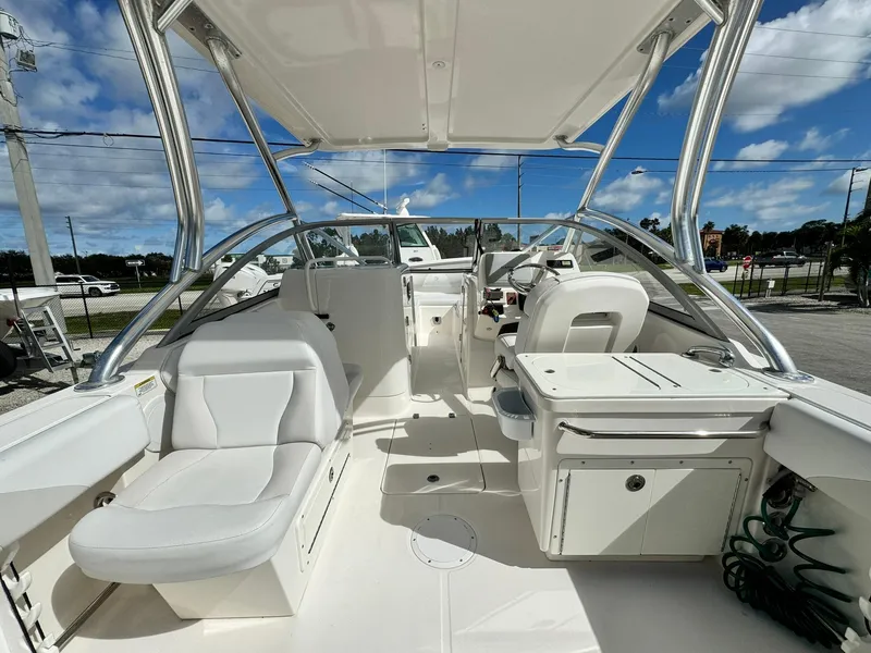Slide: The Image of 2013 Edgewater 245 CX boat interior with white seating and helm under a clear blue sky. - 13