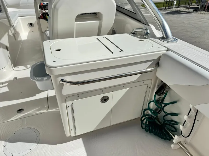 Slide: The Image of 2013 Edgewater 245 CX boat interior with storage compartment and coiled hose. - 14