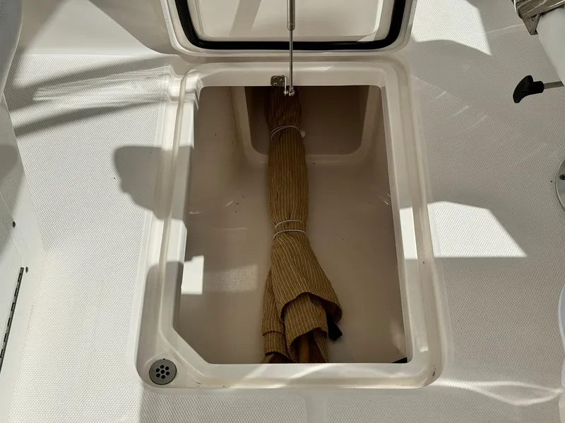 Slide: The Image of Open storage compartment on 2013 Edgewater 245 CX boat with a rolled-up mat. - 22