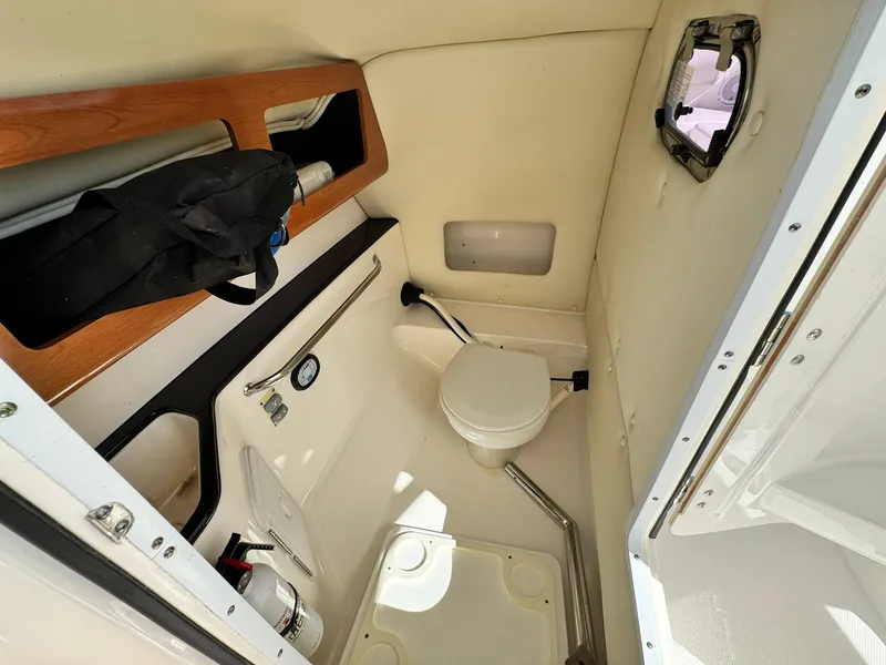 Slide: The Image of 2013 Edgewater 245 CX boat interior with compact marine toilet and storage. - 27
