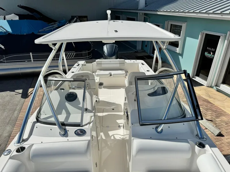 Slide: The Image of 2013 Edgewater 245 CX boat with open cockpit and dual consoles, docked near a building. - 36