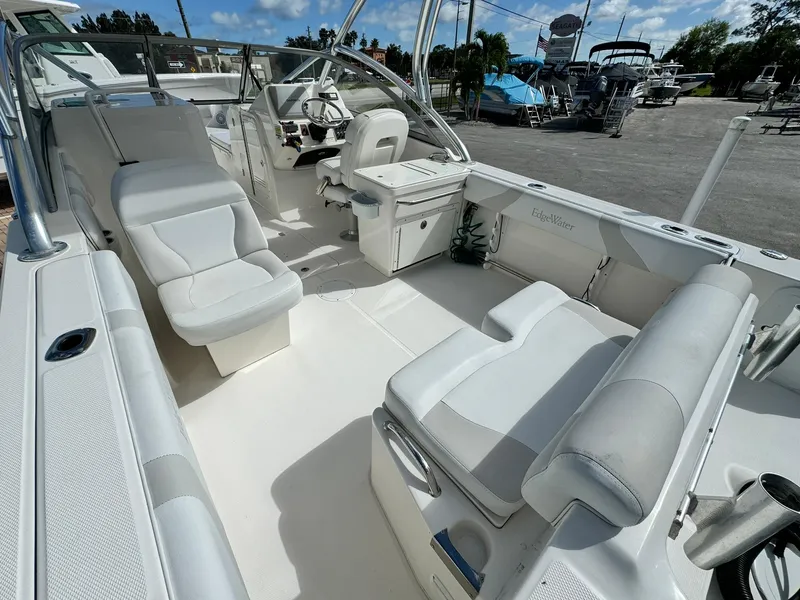 Slide: The Image of 2013 Edgewater 245 CX boat interior with white seating and helm, parked at marina. - 8