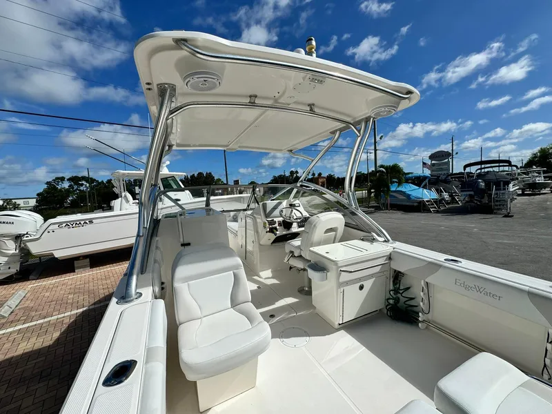Slide: The Image of 2013 Edgewater 245 CX boat with white interior, parked under a blue sky. - 9