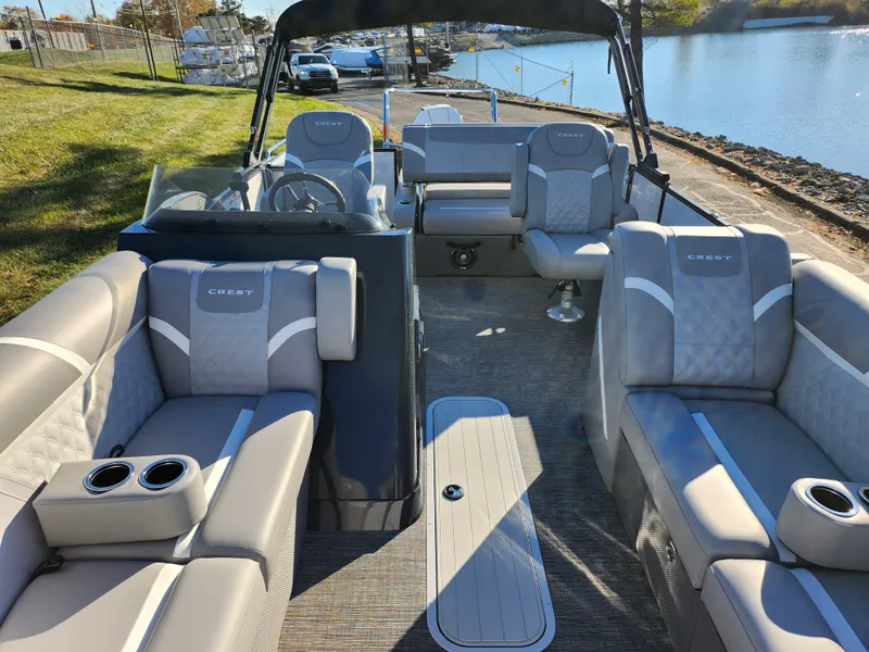 Slide: The Image of 2024 Crest Classic Platinum 220 pontoon boat with luxurious seating by a lakeside. - 10