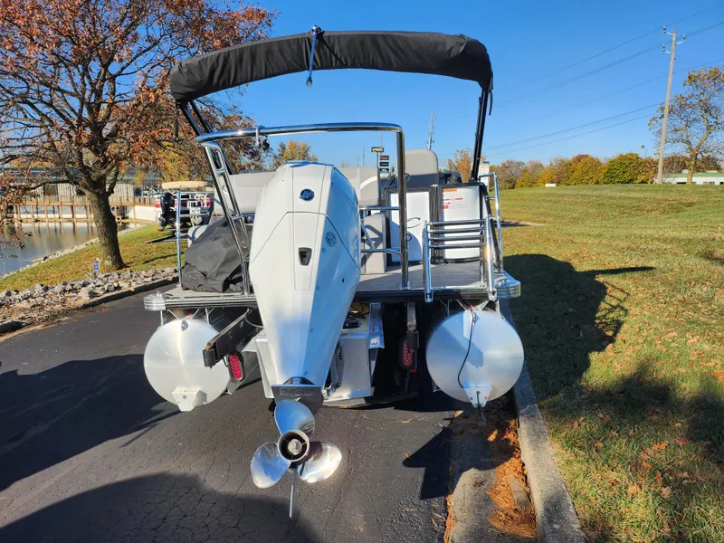 Slide: The Image of 2024 Crest Classic Platinum 220 pontoon boat with outboard motor, parked on a sunny day. - 2