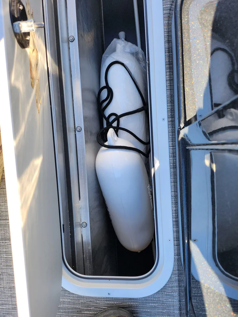 Slide: The Image of 2024 Crest Classic Platinum 220 boat storage compartment with white fender. - 24