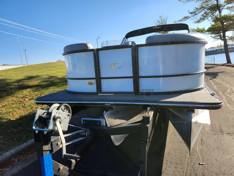 Slide: The Image of 2024 Crest Classic Platinum 220 pontoon boat on trailer, sunny day, lakeside view. - 6