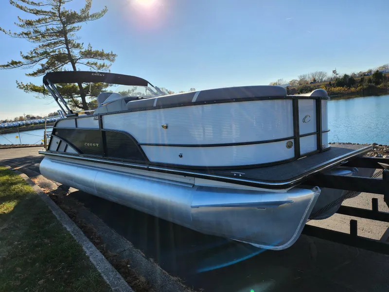 Slide: The Image of 2024 Crest Classic Platinum 220 pontoon boat by a serene lake. - 8