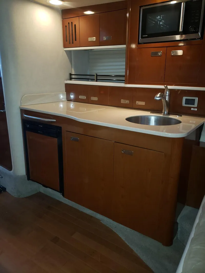 Slide: The Image of 2011 Sea Ray 350 Sundancer yacht kitchen with wood cabinets, sink, and microwave. - 13