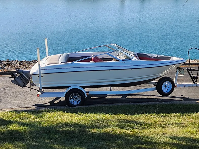 Slide: The Image of 2003 Larson SEi 180 boat on trailer by a lake. - 0