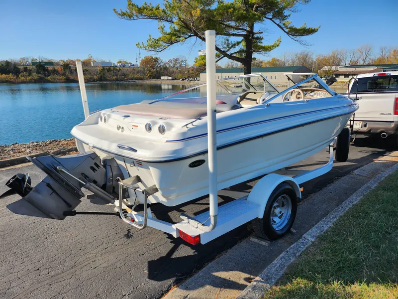 Slide: The Image of 2003 Larson SEi 180 boat on trailer by a lake. - 1