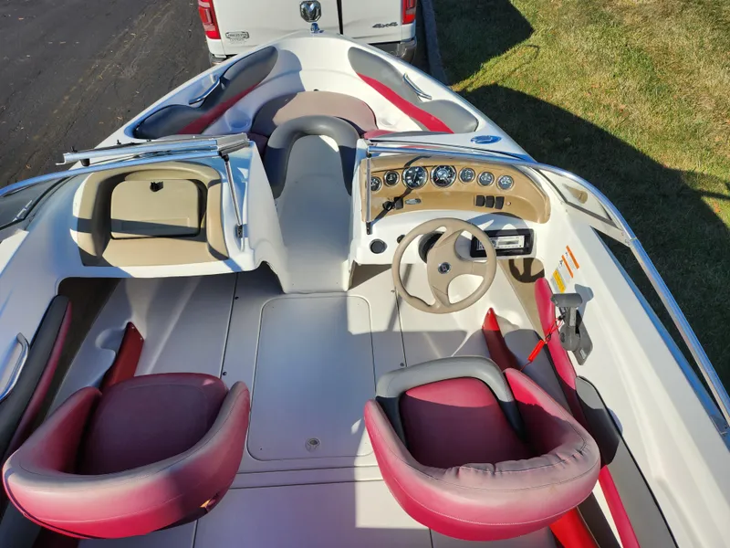 Slide: The Image of 2003 Larson SEi 180 boat interior with red and beige seating, dashboard, and steering wheel. - 11