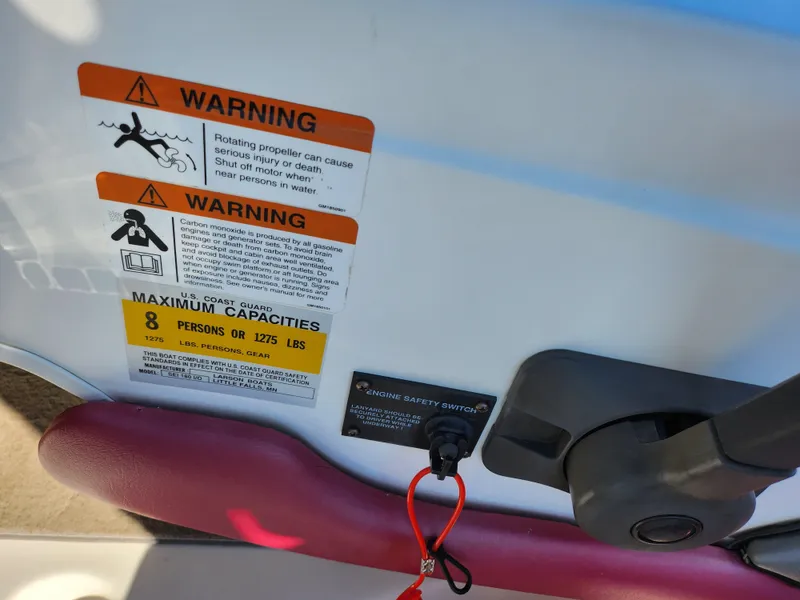 Slide: The Image of Warning labels on 2003 Larson SEi 180 boat, indicating safety and capacity limits. - 13